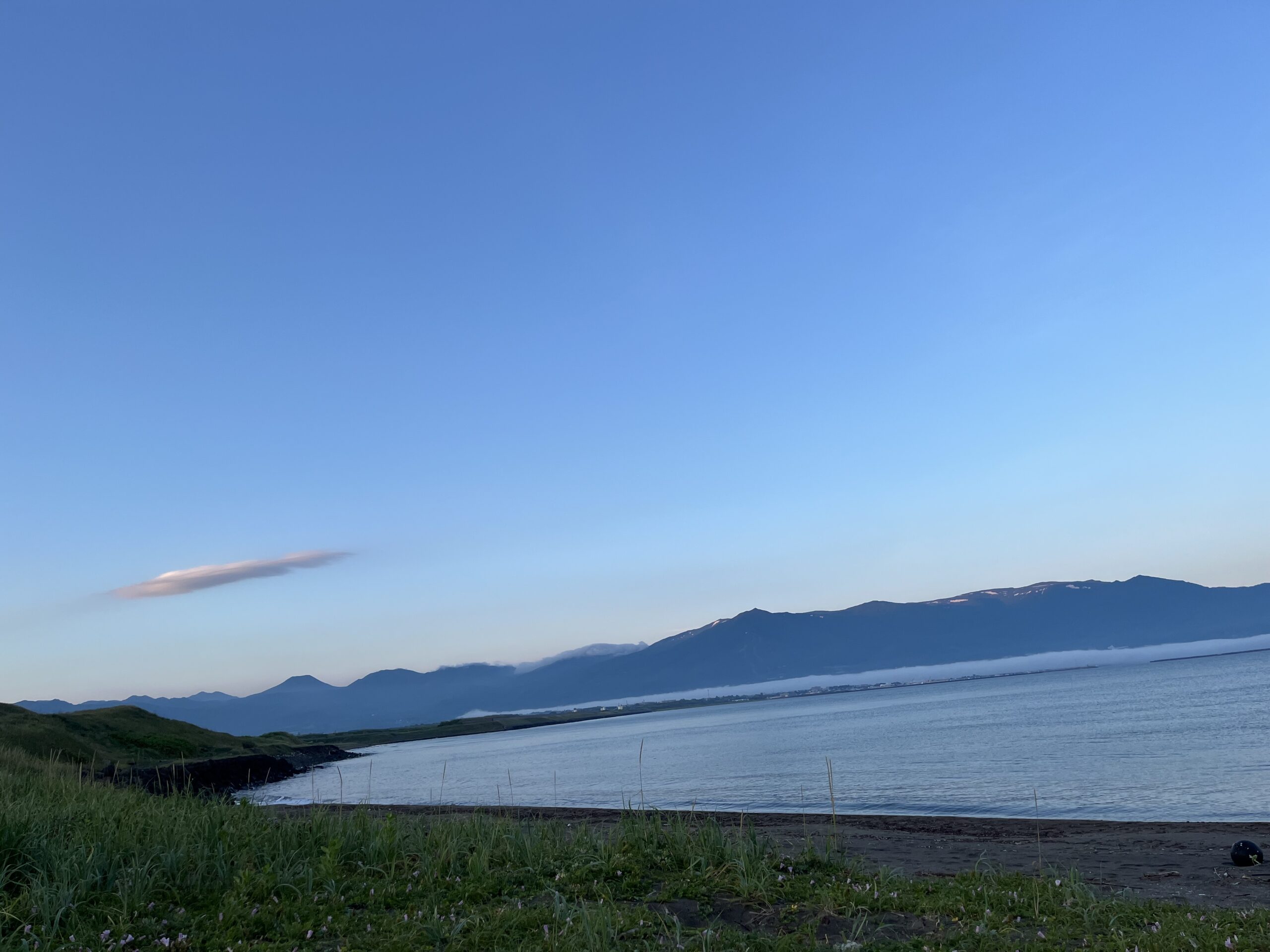 夜明けの泊村海岸と遠くに見える山