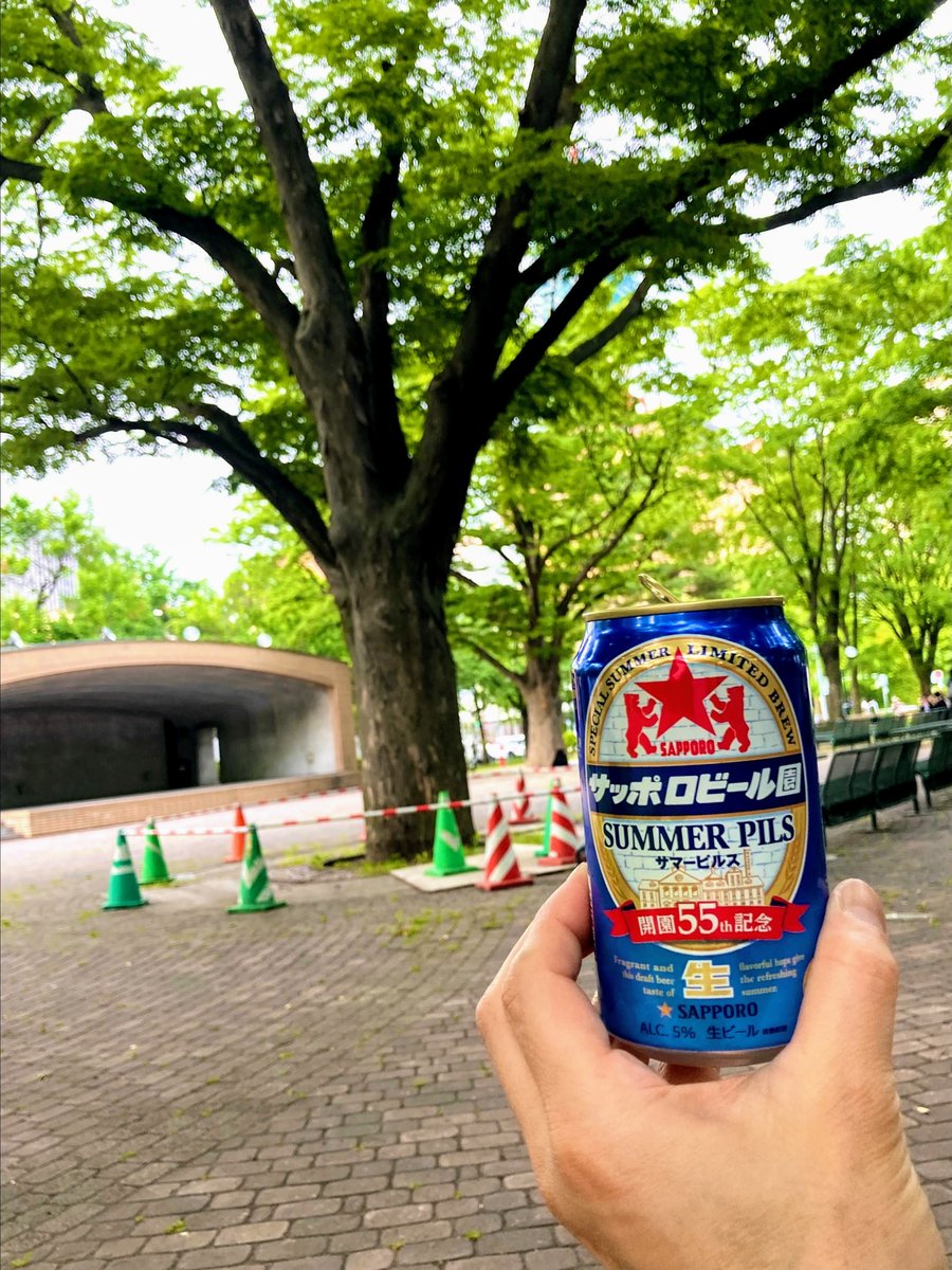 夏の公園で缶ビールを掲げる手