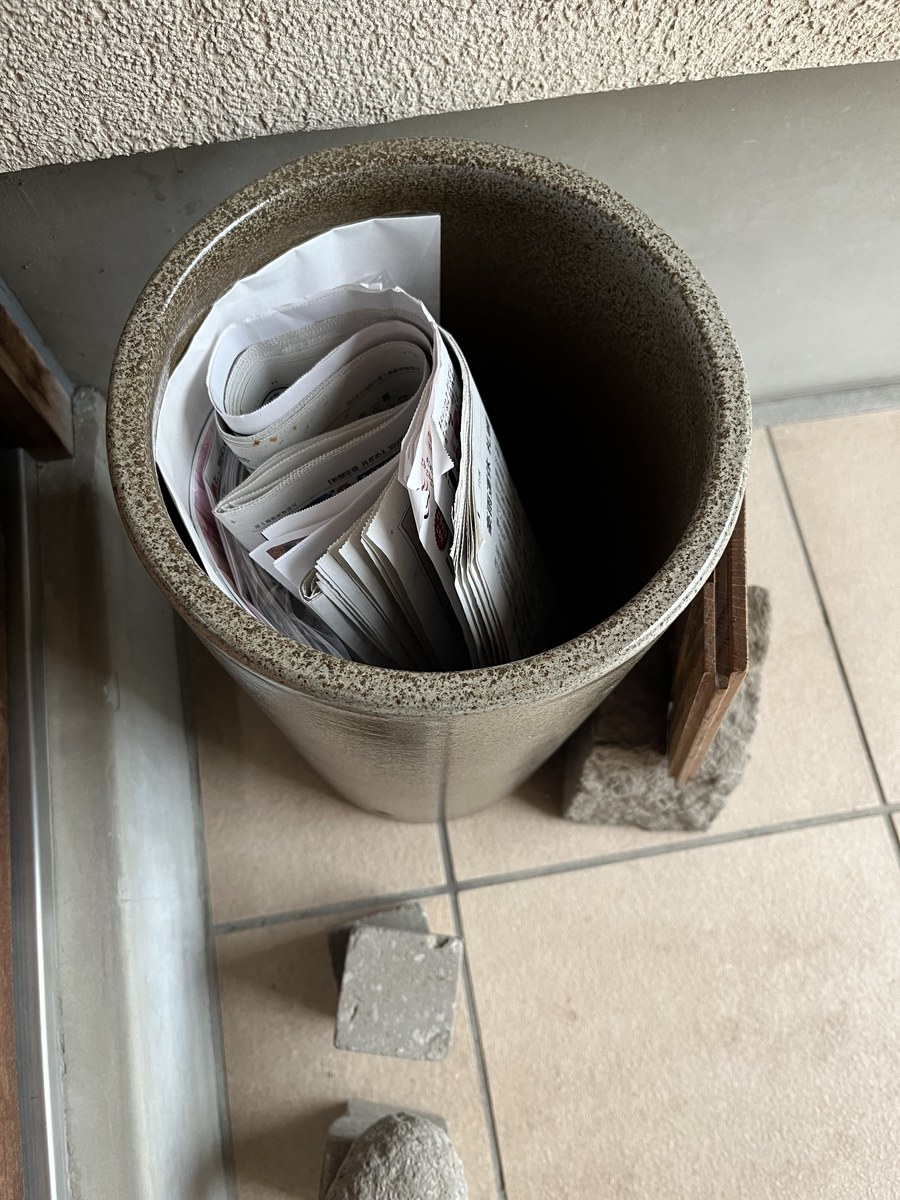 陶器の傘立ての中に丸めて入れられた新聞